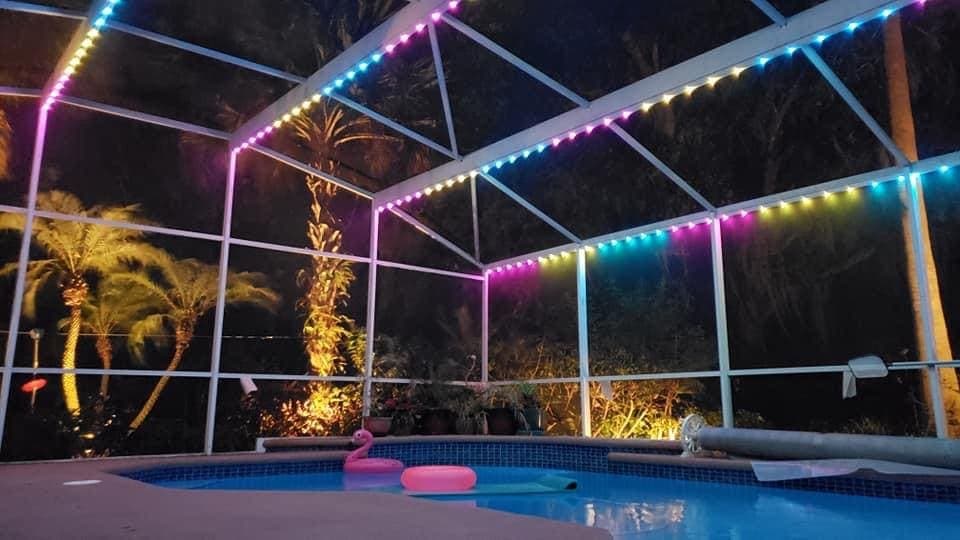 A color-lit pool enclosure over the water.