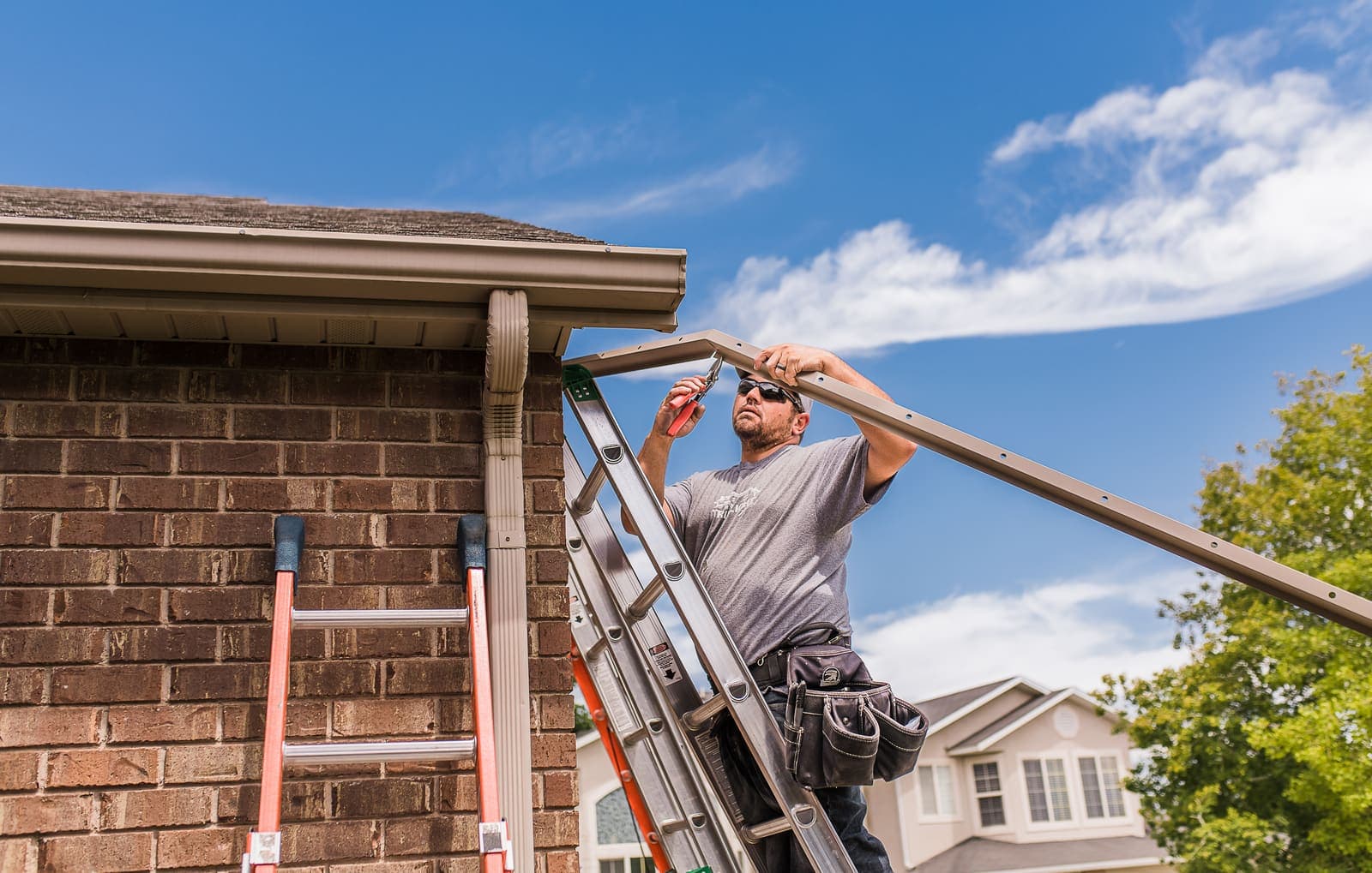 A professional installer fitting permanent lighting along a home's roofline.