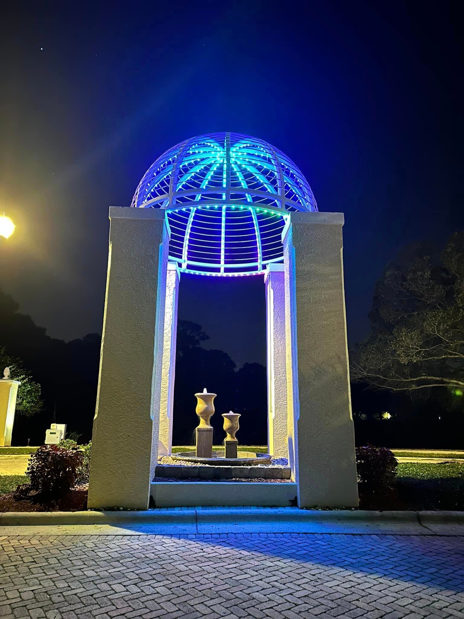 A municipal gazebo dome traced in blue lighting at night.