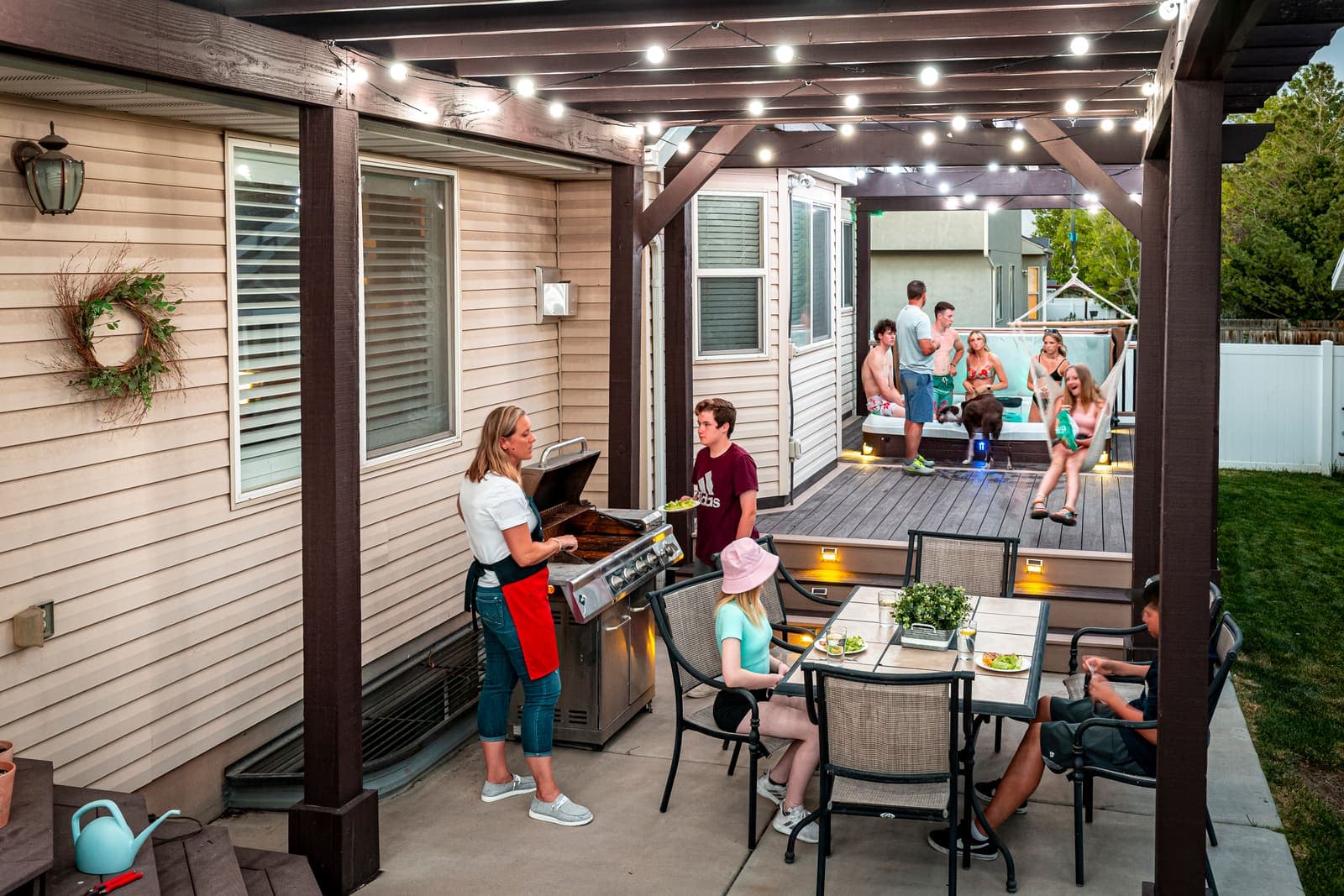 A family dinner on a patio under permanent globe lighting.