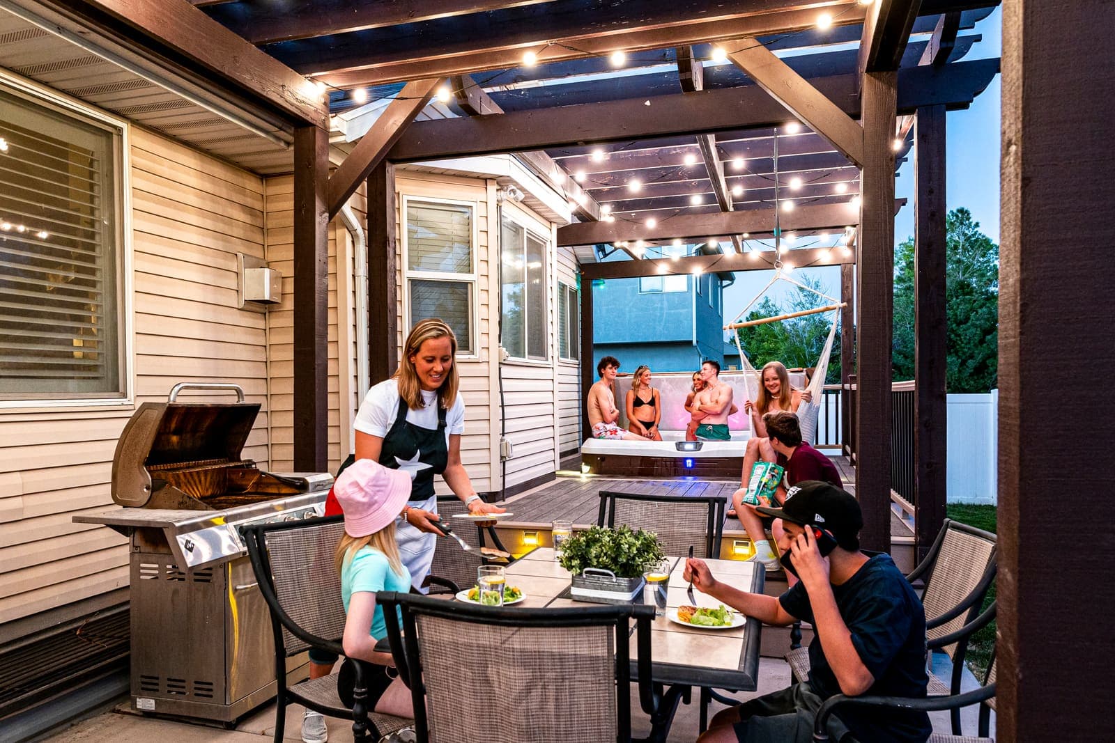 A family enjoying a covered patio under warm globe lights.