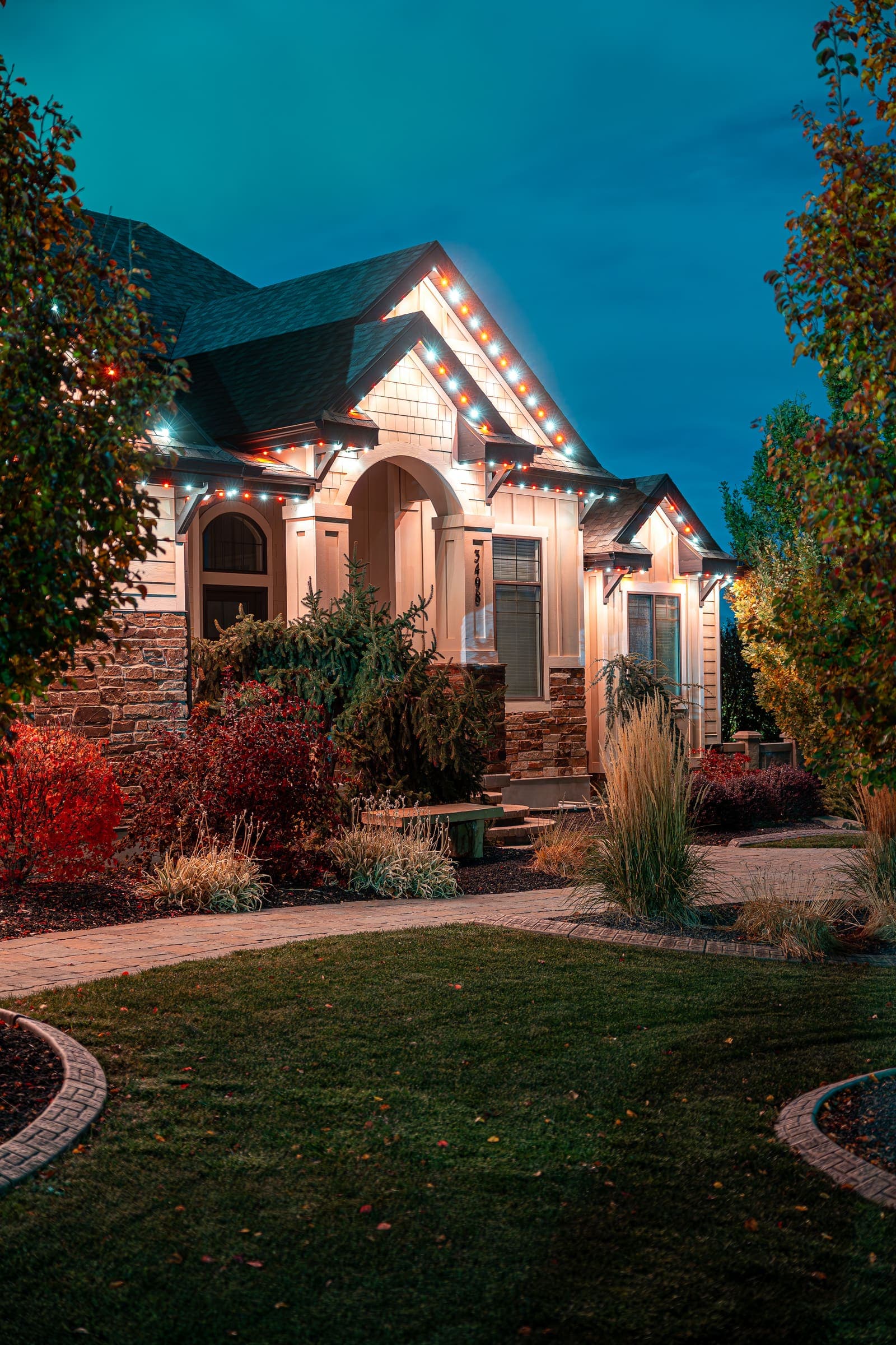 Landscape lighting illuminating trees and garden beds outside a Texas home at night.