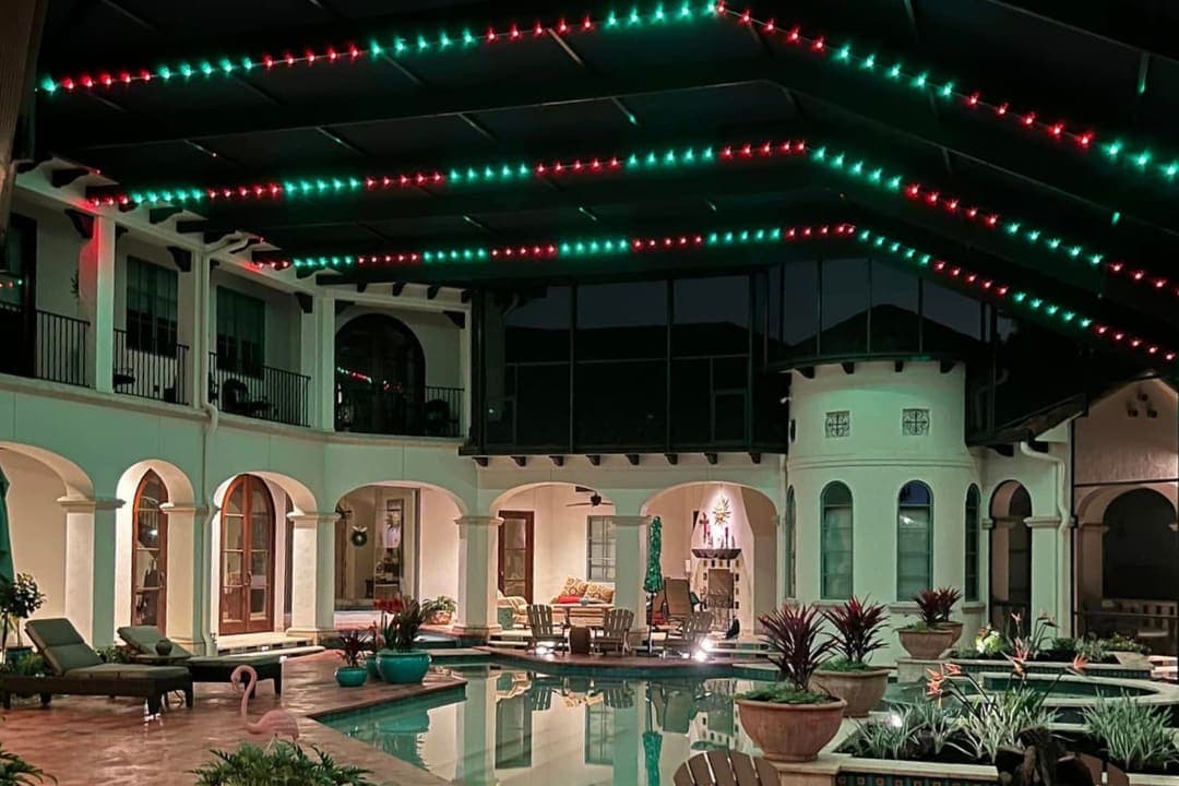 A screened pool enclosure lit at night with color LED lighting.